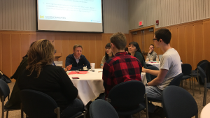Students sitting around a table in discussion with edX and Academic Innovation representatives