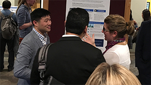 James park speaking to two individuals in front of a poster