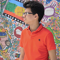 Young man looking in the distance standing in front of a wall of graffiti