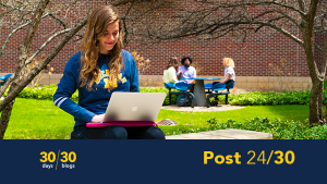 U-M student sitting on a bench working on a laptop