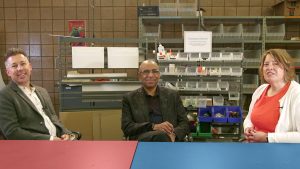 Three professors in a lab sitting at a table