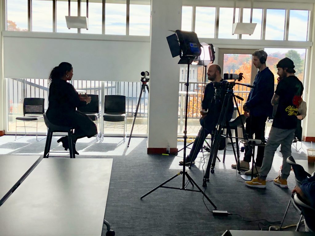 Woman sitting in a chair being filmed for teach-out