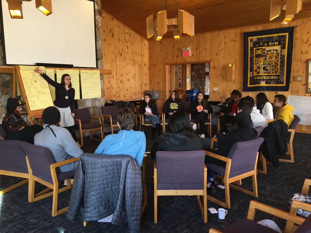 Students gathered in a circle as Elyse Aurbach leads a discusson