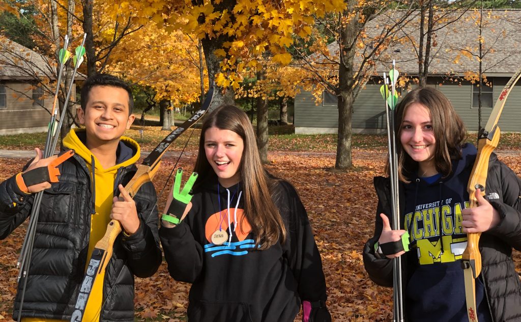 Three students posing for a photo in the woods