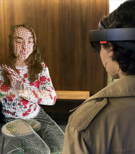 (Image of a person wearing a virtual reality headset sitting across from a virtually constructed person.)