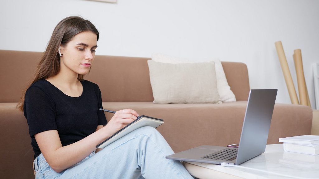 woman sitting against couch taking notes