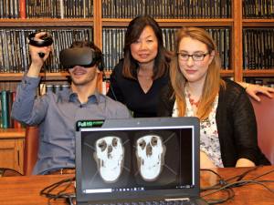 Group posed behind laptop as one person wears VR headset and laptop shows what person sees in VR