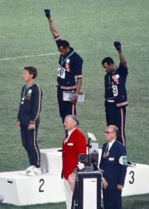Peter Norman, John Carlos and Tommie Smith on the Olympic podium at the 1968 Olympic games. Carlos and Smith are raising black-gloved fists in the air