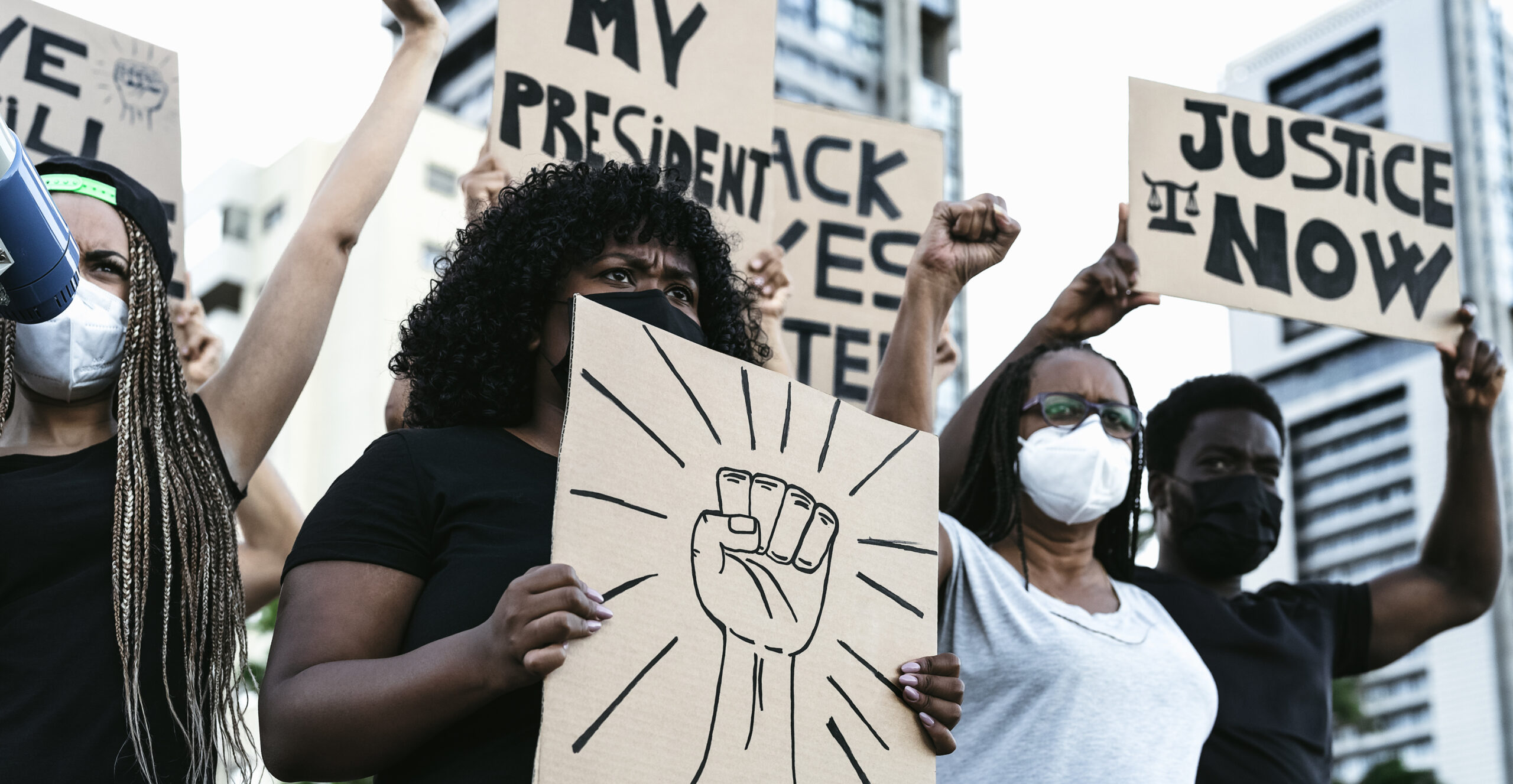 people in masks holding up signs support of black lives matter movement