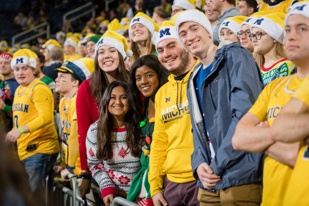 Michigan students in crowd smile for the camera.