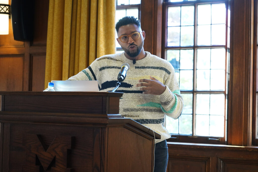 Man speaks at a podium and gestures with his hands. 