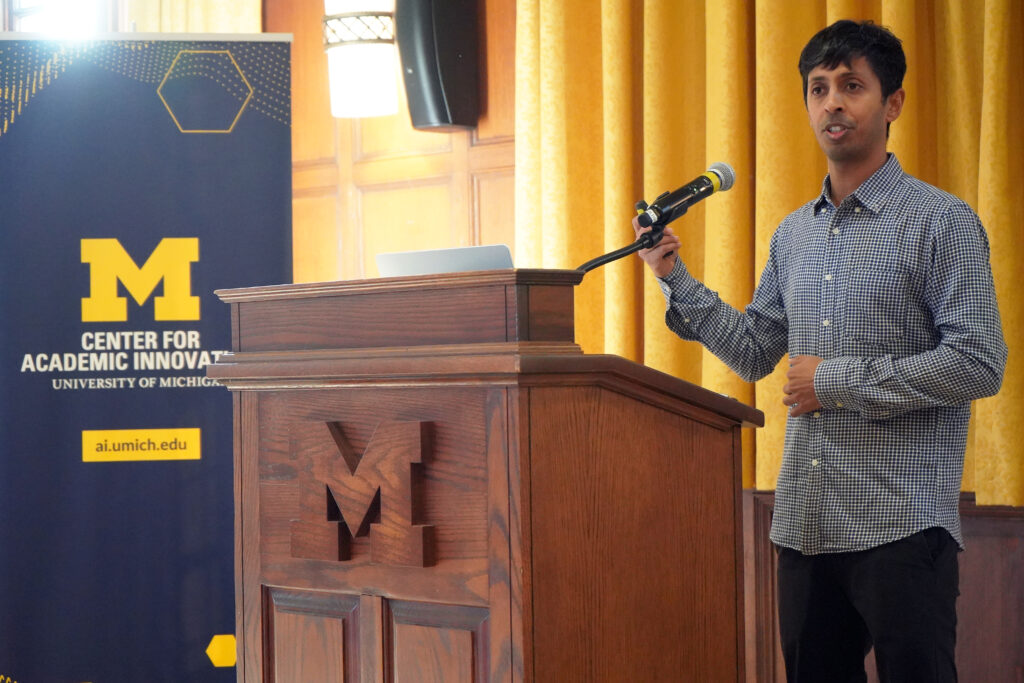 Man speaks at podium. To the left a banner for the Center for Academic Innovation - University of Michigan is seen. 