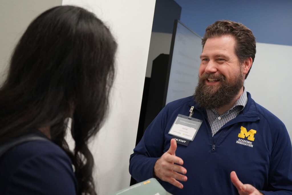 A man smiles while talking to a person across from him. 