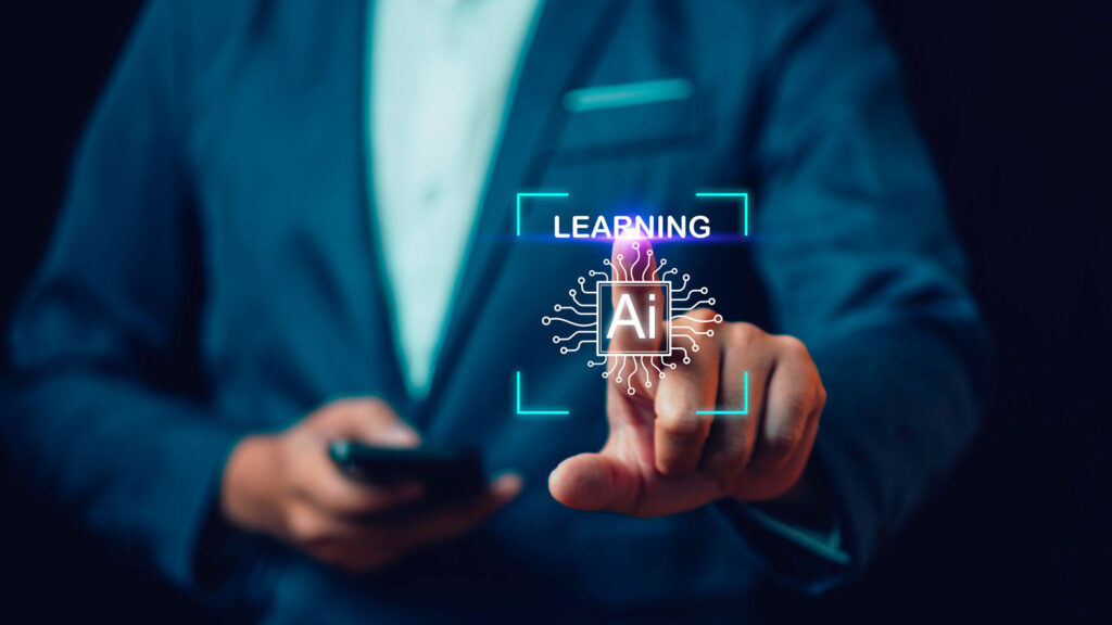 Man wearing a suit with only torso visible presses a graphic in front of him that says Learning AI