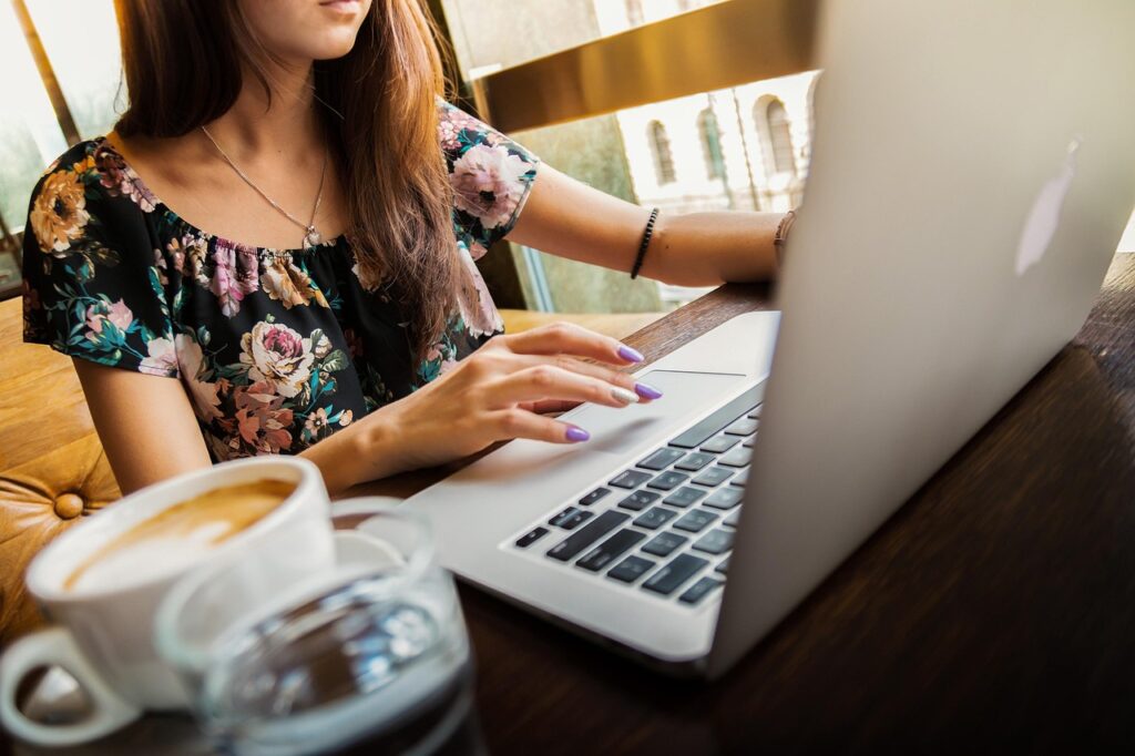 woman at desk on laptop with a coffee beside her