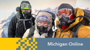 Three U-M faculty dressed in mountaineer equipment including oxygen masks and goggles post on the XR stage at the Center for Academic Innovation. An AI-produced backdrop of Mount Everest is behind them.