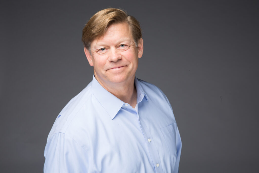 Man's portrait photo from chest up in a blue dress shirt