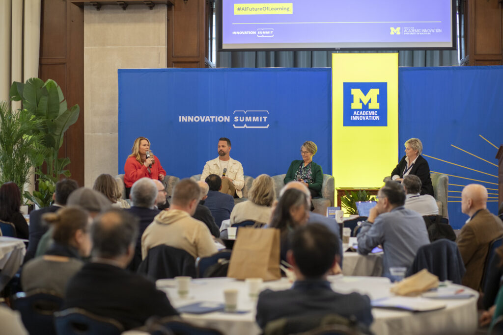 A crowd looks at four panelists on a stage giving a talk. 