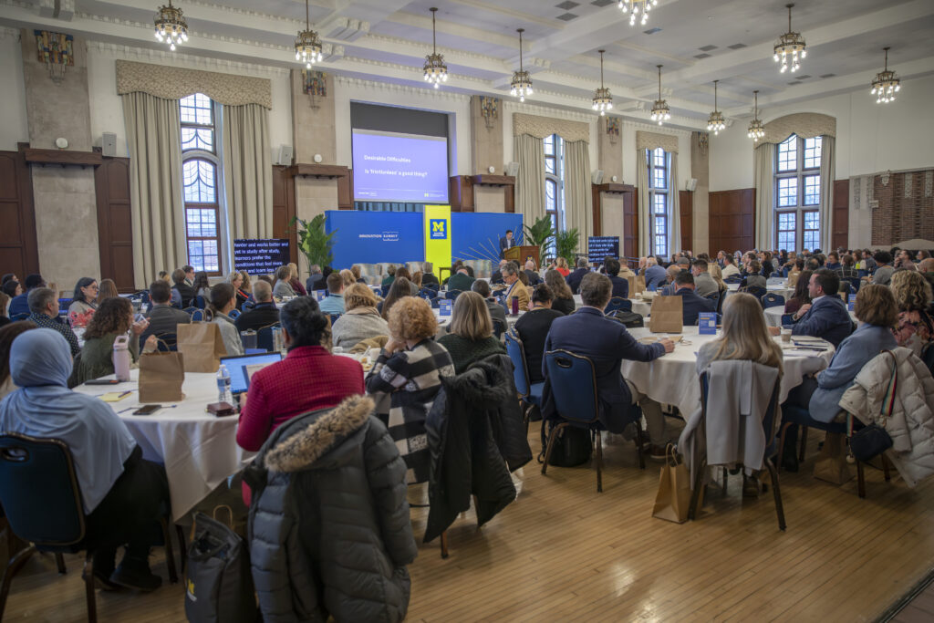 Crowd sitting around tables in a ballroom.