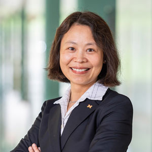 Woman smiling in a blazer with her arms folded