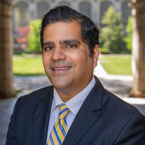 Man in suit with a maize tie with blue stripes.